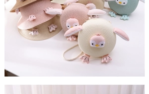 Detailed view of pink and beige kids penguin straw hat and matching round purse set