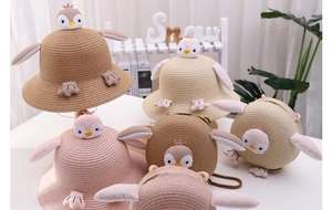 Close-up of children's penguin straw hat and matching round bag with 3D wing details