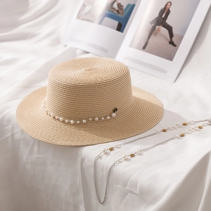 Détail d'un chapeau en paille à sommet plat avec bandeau perle et chaîne amovible