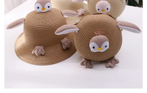 Detailed view of the cute penguin cartoon decorations on the straw sun hat and matching bag