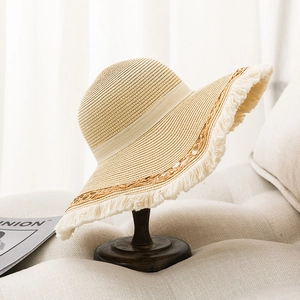 Detail shot of the frayed straw hat edge with decorative ribbon and woven texture