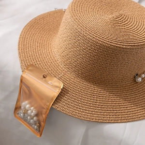 Détail d'un chapeau canotier en paille marron avec chaîne de perles et pièces de rechange