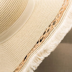 Elegant beige straw sun hat with wide fringed brim and decorative ribbon for beach vacations