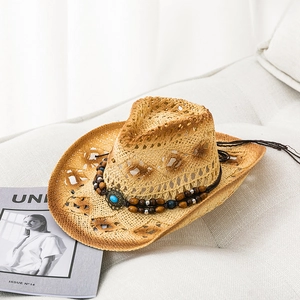 Detail of hollow-out straw cowboy hat with turquoise bead band on a textured sofa