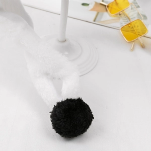 Close-up of soft white faux fur scarf with black plush pompom detail for winter