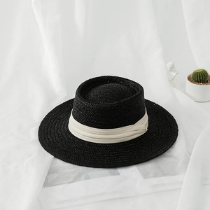 Top view of a black flat-top straw boater hat with a chic cream ribbon detail