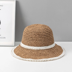 Dettaglio cappello di paglia intrecciato con nastri bianchi e perline per uno stile chic