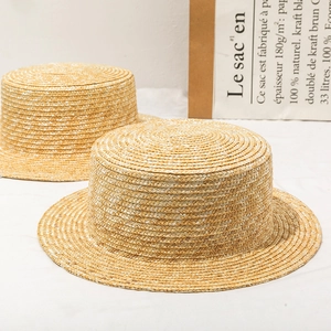 Close-up of fine woven texture on natural straw boater hats with flat top design