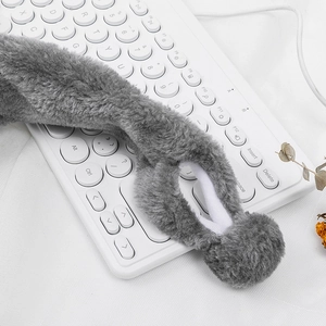 Close-up of soft grey plush bunny ears with fluffy pom-pom details on a clean background