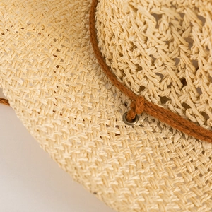 Macro detail of hand-woven straw hat texture with brown cord and bronze eyelets