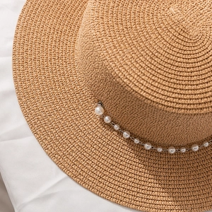 Détail d'un chapeau de paille tissé avec une chaîne de perles élégante et un sommet plat