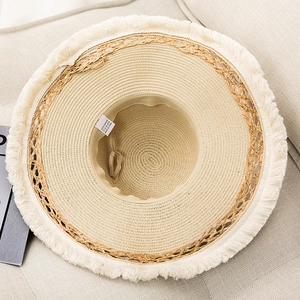Detail view of woven paper straw hat featuring frayed edges and adjustable inner strap