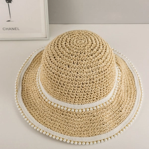 Dettaglio della trama del cappello di paglia con eleganti perle e bordo bianco rifinito