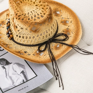 Close-up of straw sun hat with woven texture, brown ribbon, and wooden beaded decoration