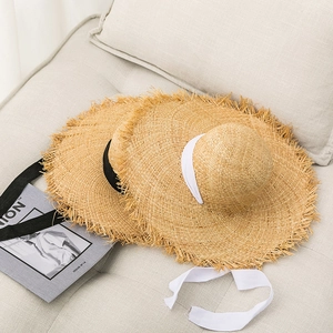 Handwoven raffia sun hat with frayed brim and lace ribbons for beach vacation