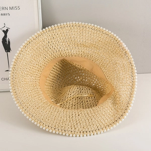 Dettaglio del cappello di paglia con bordo di perle e laccio di regolazione interno
