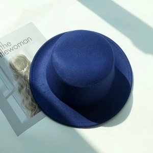 Deep blue felt fedora hat shown on a white background with a fashion magazine prop