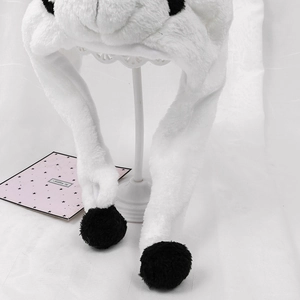 Detailed view of white plush panda hat with long ear flaps and black pom-pom decorations