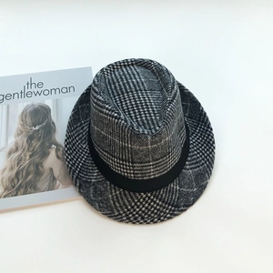 Detail of grey plaid wool fedora hat with black band on a fashion magazine background