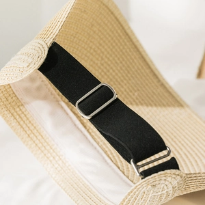 Detail of adjustable black elastic strap with silver metal buckle on straw sun hat