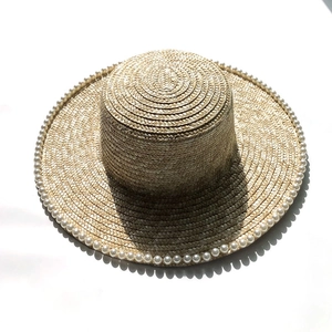 Summer wheat straw sun hat with wide brim and elegant pearl trimming on white background