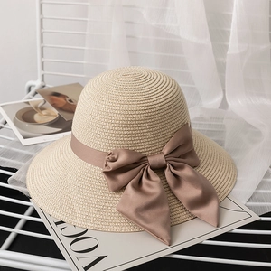 Close-up of beige straw sun hat featuring a large dark brown silk ribbon bow detail