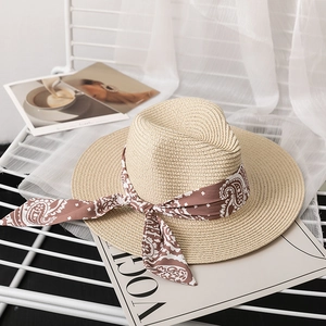 Detail of beige straw fedora with paisley ribbon on a stylish white metal chair