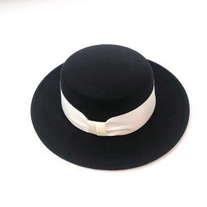 Close-up of black wool felt boater hat with a cream ribbon band and flat top crown