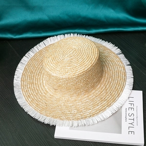 Straw flat top sun hat with white fringe trim and woven texture for summer vacation use