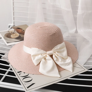 Elegant wide brim straw hat in pink with a large cream silk bow for sun protection