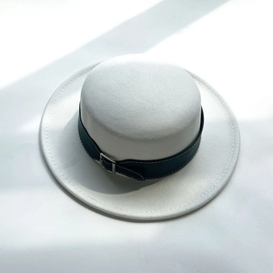 Detail of white wool felt boater hat featuring a black belt strap and silver buckle