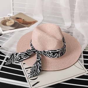 Detail of pink straw sun hat with stylish black and white paisley ribbon and wide brim