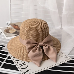 Close-up of woven straw sun hat with elegant silk bow ribbon on a stylish rack