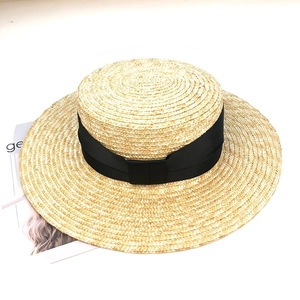 Détail d'un chapeau de paille à sommet plat avec un large ruban en gros-grain noir