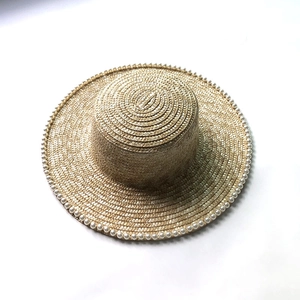 Detail of wide brim straw hat featuring elegant pearl trim on fine wheat straw