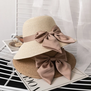 Elegant wide-brim straw hat with large silk bow decoration for summer beach sun protection
