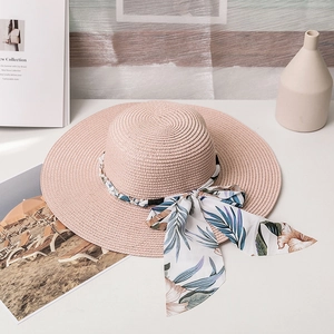 Détail d'un chapeau de paille rose avec ruban fleuri tropical et perles blanches