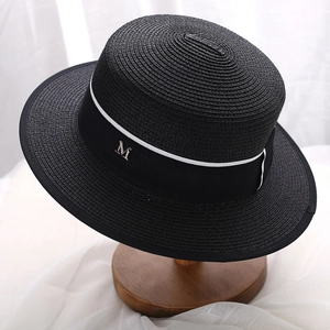 Classic black straw boater hat with striped ribbon and metallic M emblem on wooden stand
