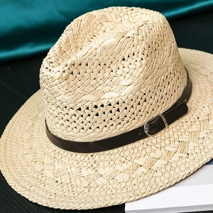 Detail of light straw Fedora hat featuring a dark brown leather band and silver buckle