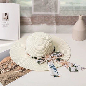 Détail d'un chapeau de paille tissé avec décorations en perles et ruban de soie floral