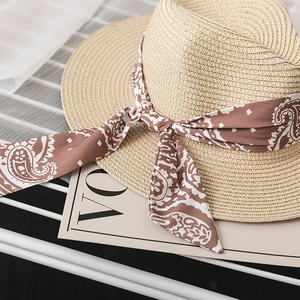 Detailed texture of woven straw hat with a paisley pattern silk ribbon and bow tie