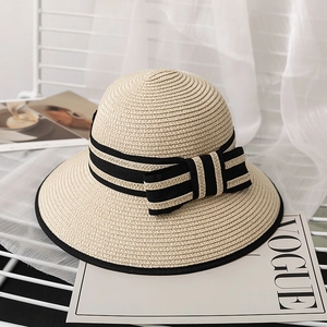 Straw cloche hat with black striped ribbon and bow on a white vintage stand