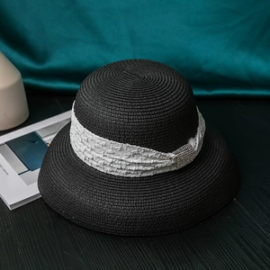 Detail of black woven straw hat with white pleated ribbon and sparkling diamond buckle