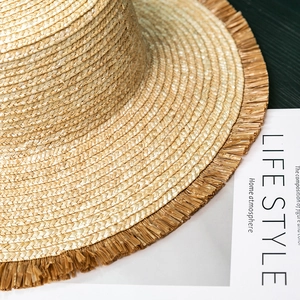 Close-up of hand-woven straw hat showing detailed fringe edges and natural wheat texture