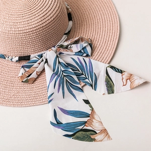 Détail d'un chapeau de soleil en paille avec ruban floral et bordure en perles