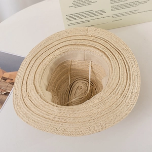 Detailed interior of a beige straw beach hat showing the sweatband and adjustable strap