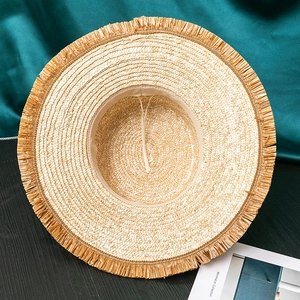 Top view of wide brim straw hat showing tassel edges and inner adjustable sweatband