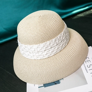 Detail of light beige straw hat with white crêpe ribbon on a vintage wooden surface