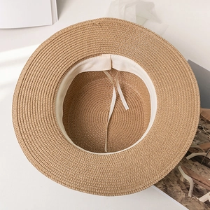 Detail view of the brown straw hat interior featuring a white sweatband and adjustable drawstrings