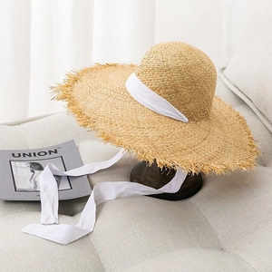 Sombrero de rafia beige con ala ancha deshilachada y elegantes cintas blancas